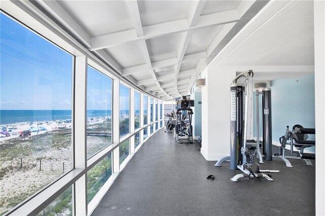 exercise room featuring a water view, healthy amount of natural light, beam ceiling, and coffered ceiling