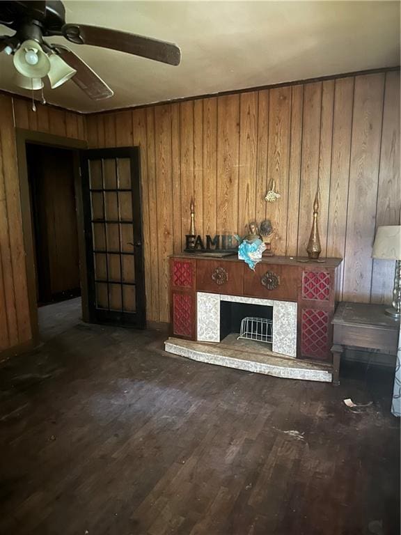 unfurnished living room featuring wood walls, a tile fireplace, ceiling fan, and hardwood / wood-style floors