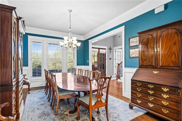 dining space with wainscoting, a notable chandelier, plenty of natural light, and wood finished floors