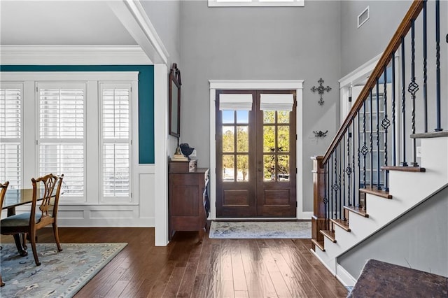 foyer entrance with french doors, dark wood finished floors, visible vents, ornamental molding, and stairs