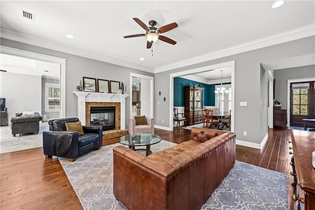 living area featuring visible vents, crown molding, baseboards, and wood finished floors