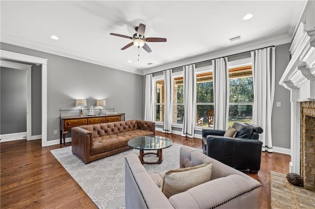 living room with baseboards, a fireplace with raised hearth, ceiling fan, wood finished floors, and crown molding