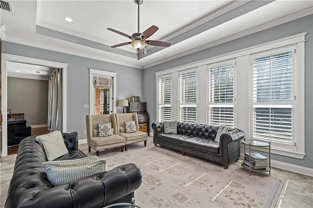 living area with a healthy amount of sunlight, baseboards, a tray ceiling, and crown molding