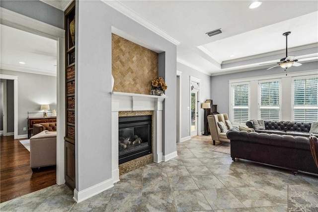 living area featuring ornamental molding, a premium fireplace, visible vents, and baseboards