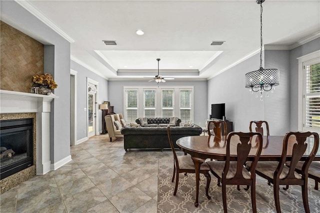 dining room featuring visible vents, a ceiling fan, a premium fireplace, ornamental molding, and a tray ceiling