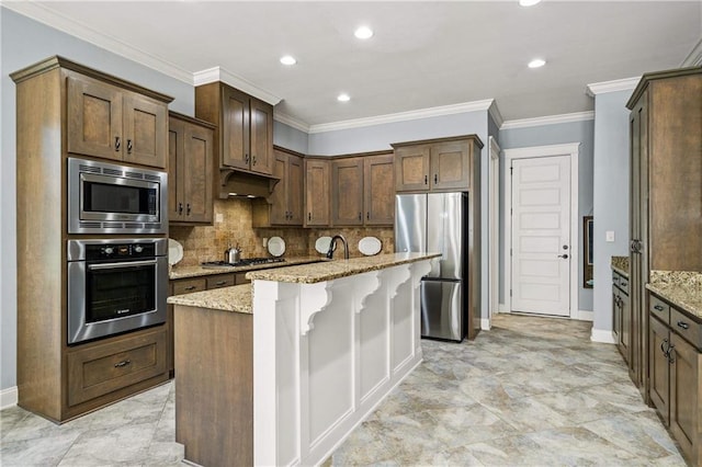 kitchen with an island with sink, light stone counters, stainless steel appliances, and a breakfast bar area