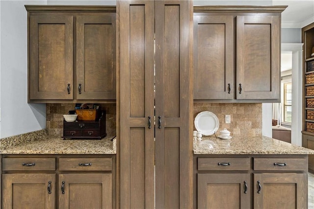 kitchen with crown molding, light stone counters, and backsplash