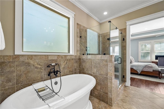 ensuite bathroom with a stall shower, connected bathroom, crown molding, a freestanding tub, and tile walls