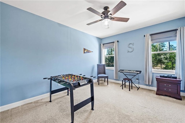 game room with light carpet, a ceiling fan, and baseboards