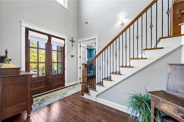 foyer entrance with french doors, visible vents, stairway, dark wood-type flooring, and baseboards