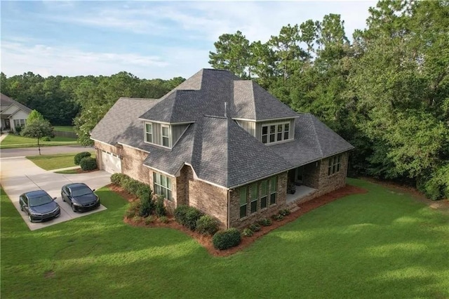 exterior space featuring a garage, a shingled roof, brick siding, concrete driveway, and a yard