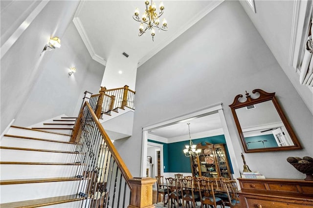 stairway with a chandelier, visible vents, crown molding, and a high ceiling