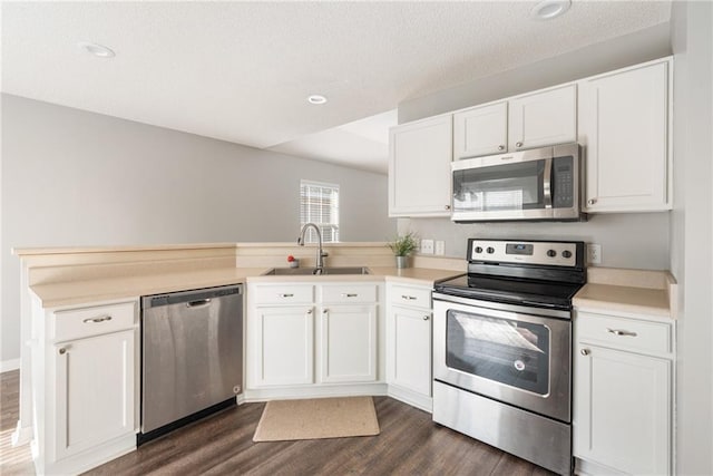 kitchen with kitchen peninsula, sink, appliances with stainless steel finishes, white cabinets, and dark hardwood / wood-style flooring