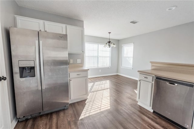 kitchen featuring pendant lighting, dark wood-type flooring, white cabinetry, stainless steel appliances, and a chandelier