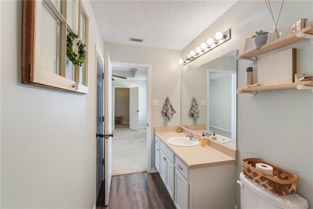 bathroom featuring a textured ceiling, toilet, wood-type flooring, and vanity