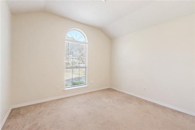 carpeted spare room featuring vaulted ceiling