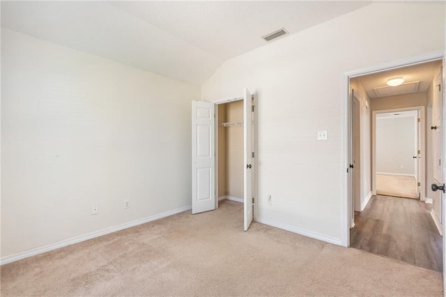 unfurnished bedroom with a closet, lofted ceiling, and light colored carpet