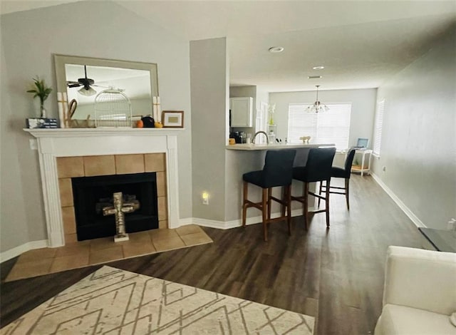 living room with wood-type flooring, a tile fireplace, and a notable chandelier