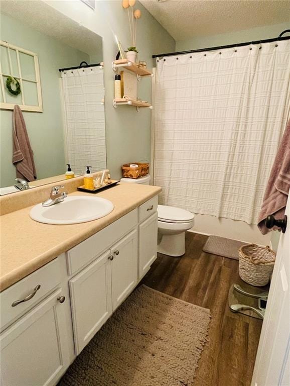 bathroom featuring toilet, vanity, wood-type flooring, and a textured ceiling