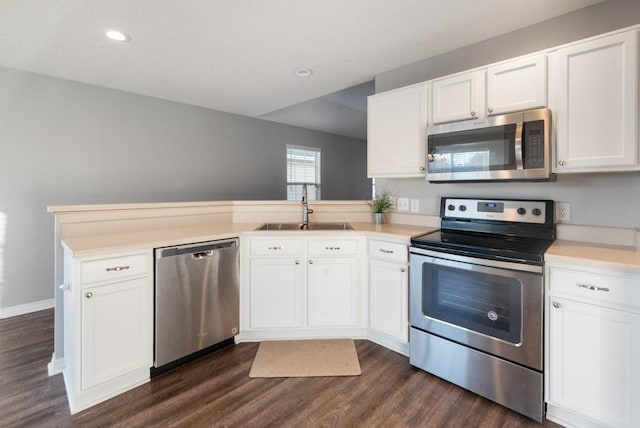 kitchen featuring white cabinets, appliances with stainless steel finishes, sink, dark hardwood / wood-style floors, and kitchen peninsula