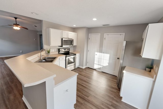 kitchen featuring white cabinetry, kitchen peninsula, appliances with stainless steel finishes, dark hardwood / wood-style floors, and sink