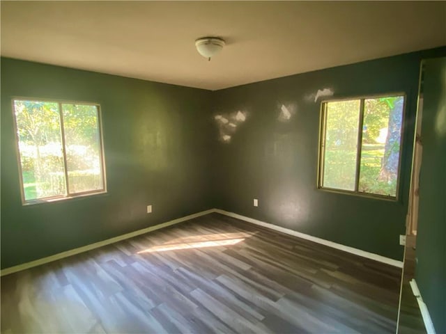 spare room featuring dark hardwood / wood-style floors and a healthy amount of sunlight