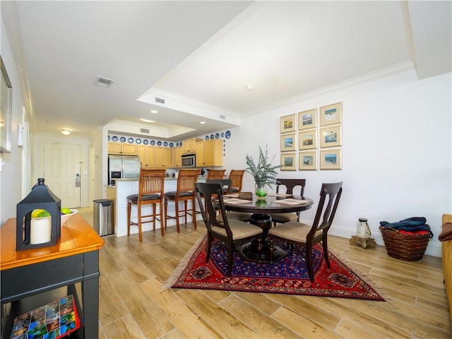 dining space featuring light wood-type flooring and crown molding