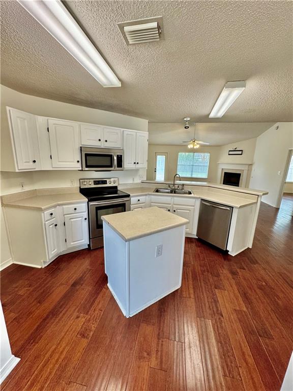 kitchen with white cabinetry, sink, dark hardwood / wood-style flooring, kitchen peninsula, and stainless steel appliances