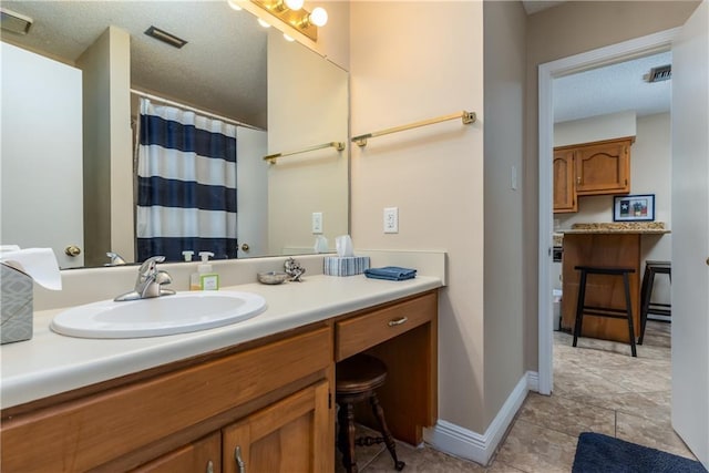 bathroom featuring baseboards, visible vents, a textured ceiling, and vanity