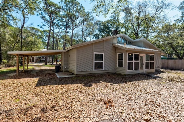 view of home's exterior featuring a sunroom, fence, and a carport