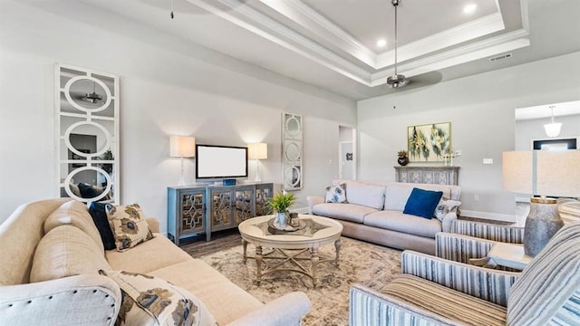 living room featuring ornamental molding, wood-type flooring, ceiling fan, and a raised ceiling