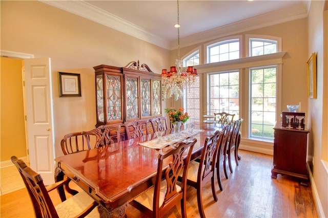 dining room with ornamental molding, wood-type flooring, and a notable chandelier