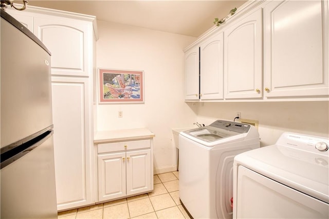 laundry room featuring cabinets, light tile patterned floors, and washer and clothes dryer