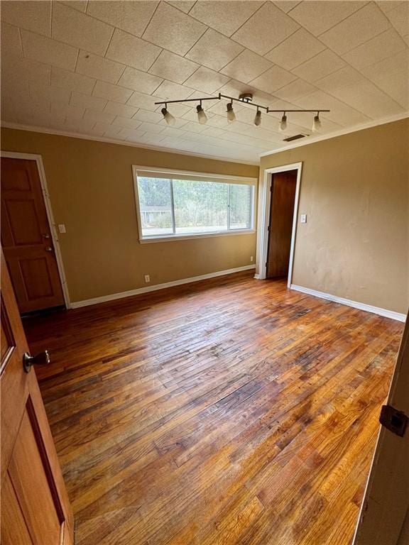 spare room featuring ornamental molding, wood-type flooring, and track lighting