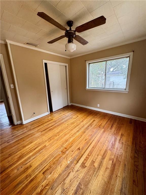 unfurnished bedroom featuring light hardwood / wood-style flooring, ornamental molding, a closet, and ceiling fan