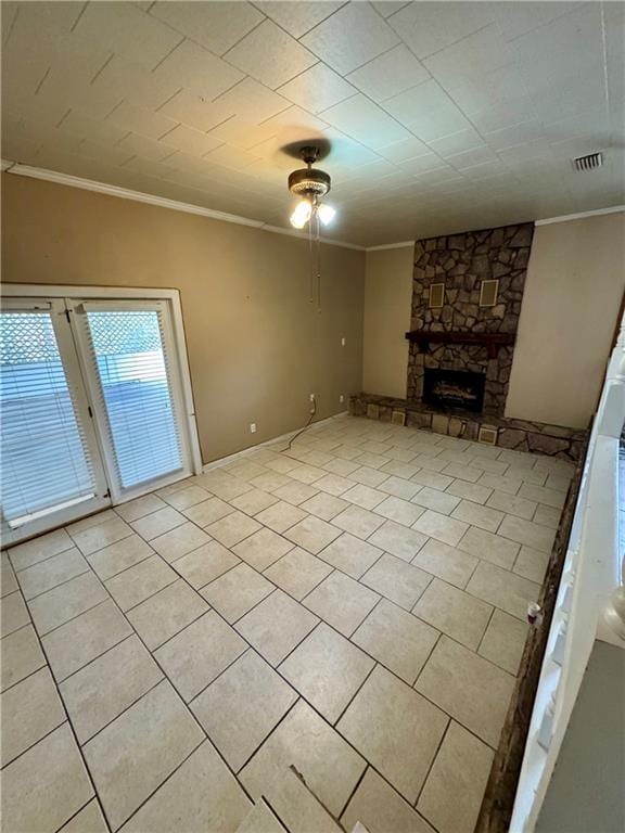 unfurnished living room with crown molding, a stone fireplace, and light tile patterned flooring