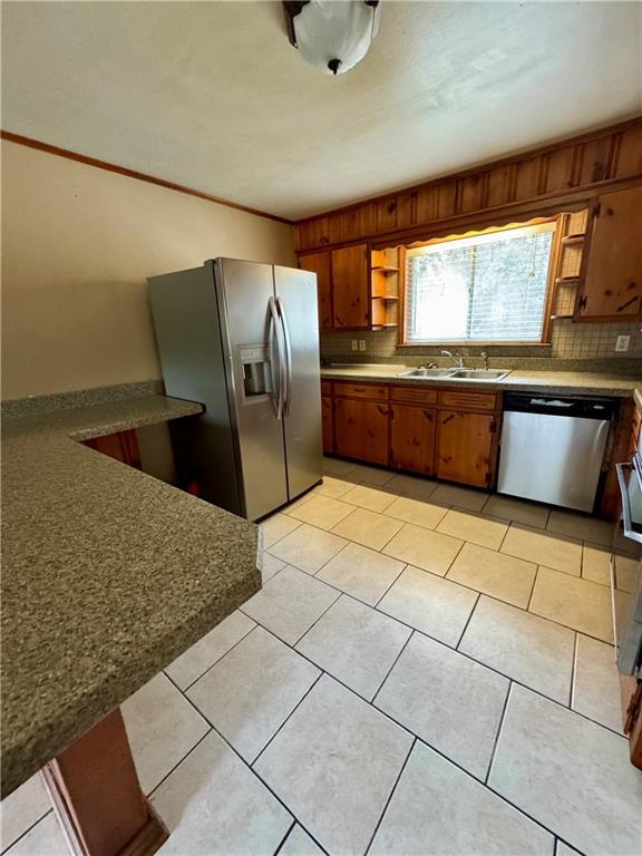 kitchen with tasteful backsplash, sink, light tile patterned floors, and stainless steel appliances