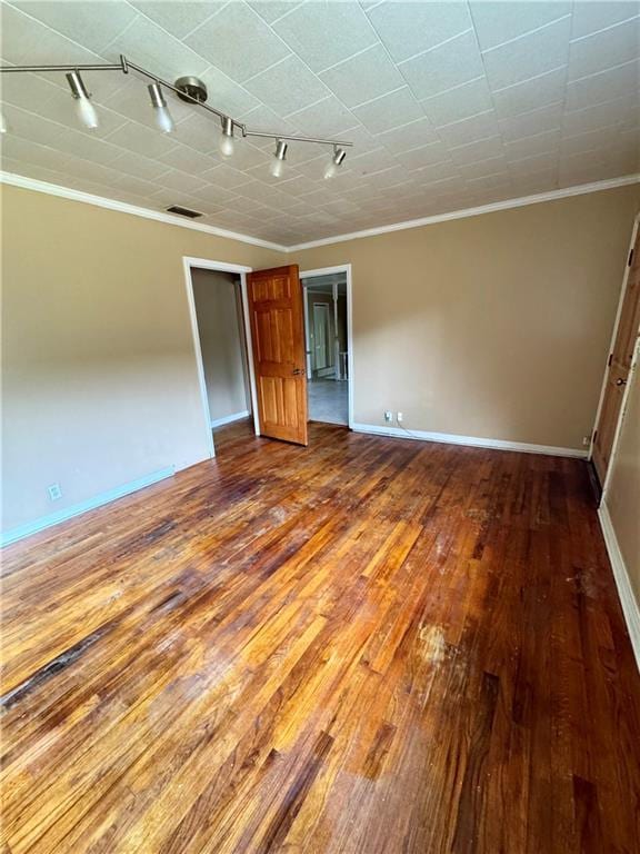 empty room featuring crown molding, hardwood / wood-style floors, and track lighting