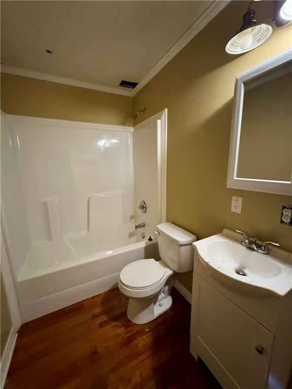 full bathroom with hardwood / wood-style flooring, vanity, ornamental molding,  shower combination, and toilet