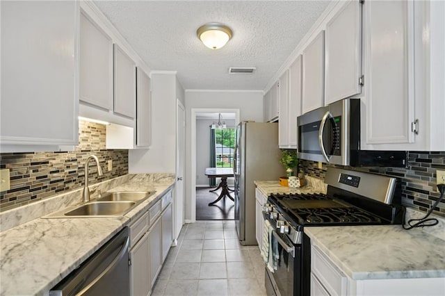 5717 Post Oak Ct, Mobile, AL 36609 - kitchen featuring stainless steel appliances, a sink, a textured ceiling, decorative backsplash, and light tile patterned flooring
