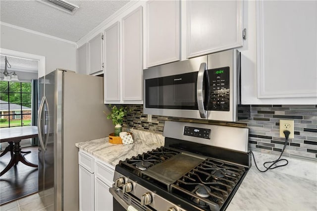 5717 Post Oak Ct, Mobile, AL 36609 - kitchen with appliances with stainless steel finishes, a textured ceiling, white cabinetry, light stone countertops, and backsplash