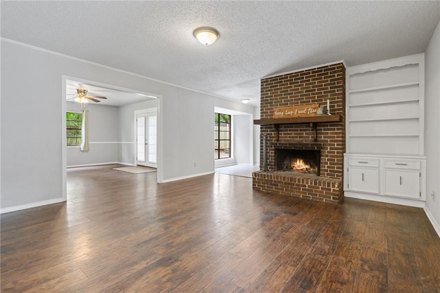 5717 Post Oak Ct, Mobile, AL 36609 - unfurnished living room featuring dark wood-style floors, a textured ceiling, a fireplace, baseboards, and built in shelves