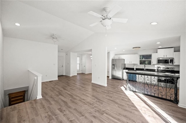 living room featuring ceiling fan, light hardwood / wood-style floors, and vaulted ceiling