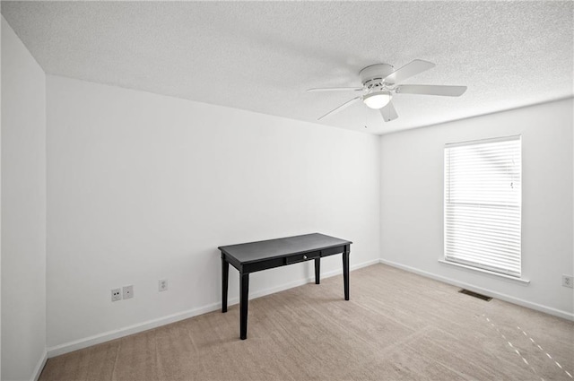 interior space featuring ceiling fan, light colored carpet, and a textured ceiling