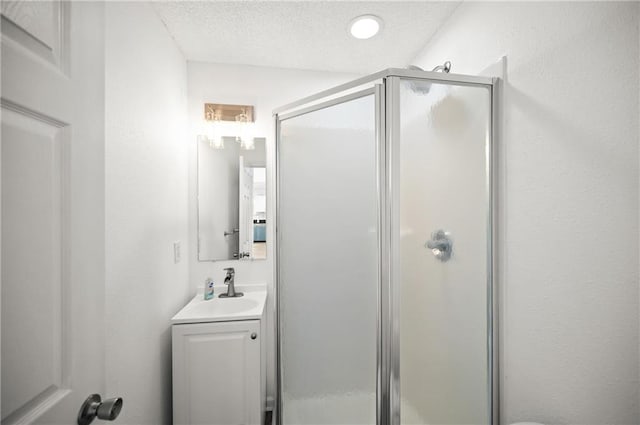 bathroom featuring an enclosed shower, vanity, and a textured ceiling