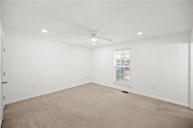 spare room with light colored carpet and ceiling fan