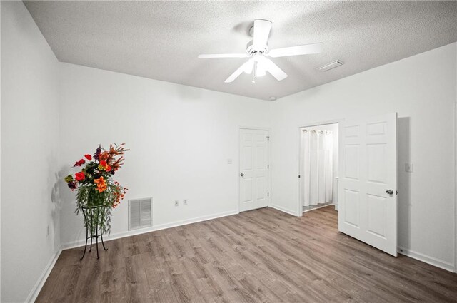 empty room featuring ceiling fan, a textured ceiling, and light wood-type flooring