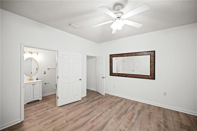 unfurnished bedroom with ceiling fan, connected bathroom, a textured ceiling, and light hardwood / wood-style flooring