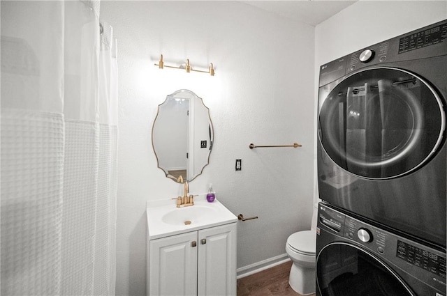 bathroom with vanity, stacked washer and clothes dryer, and toilet