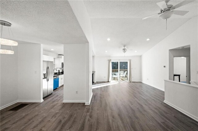 unfurnished living room featuring ceiling fan, vaulted ceiling, a textured ceiling, and dark hardwood / wood-style flooring